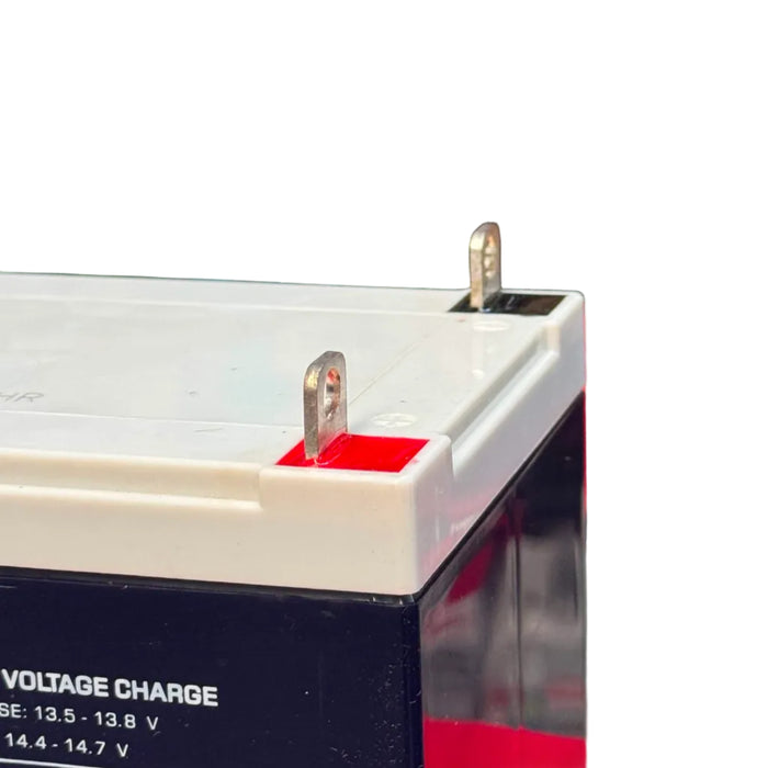Close-up of a battery with visible terminals and voltage information on a blurred background.